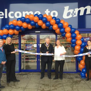 Lord Provost James Robertson joins Booby Mason from St Andrew's Hospice charity to cut the ribbon and officially re-open B&M Airdrie Retail Park store