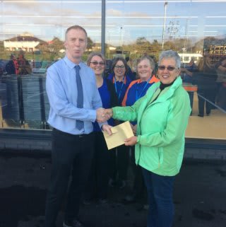 Representatives Teresa and Donna from the Wadebridge Food Bank charity accept £250 worth of B&M vouchers from store manager Jake Smith.